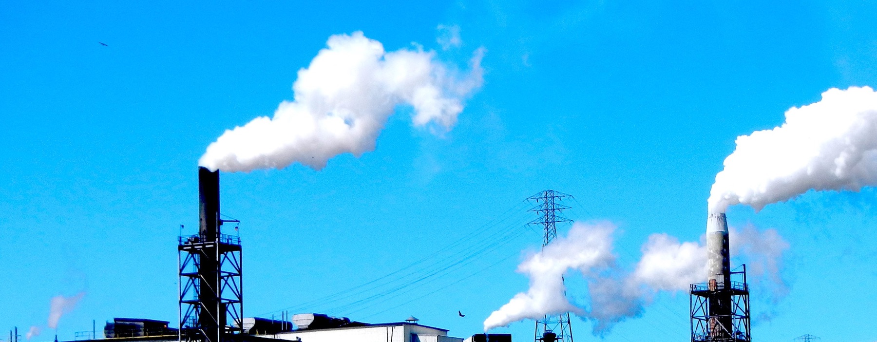 Smokestacks releasing white plumes against a blue sky
